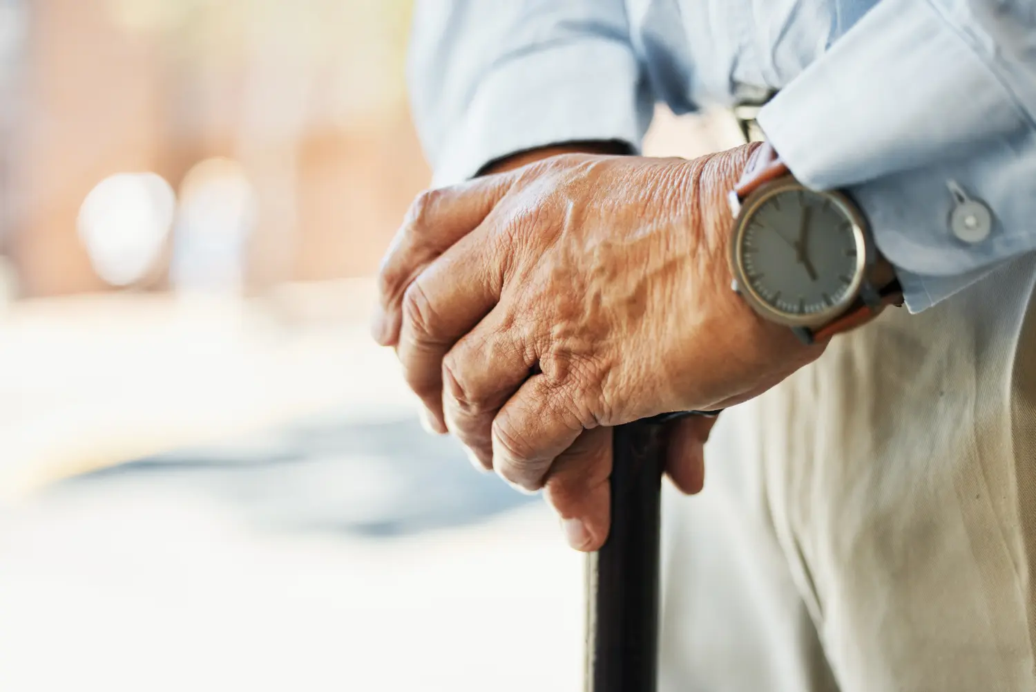 Senior, Hände und Ständer mit Stock in Nahaufnahme für Ruhestand, Urlaub oder Reise auf verschwommenem Hintergrund.